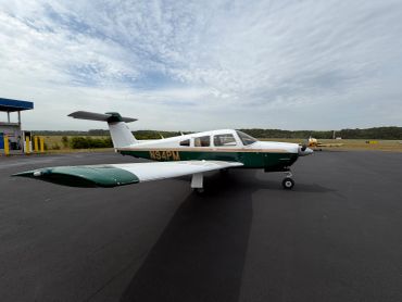 Small green and white airplane on runway.