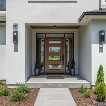 Modern house entrance with a stylish wooden front door and well-maintained landscaping.