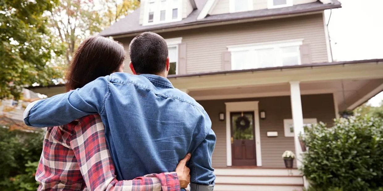 Couple embracing in front of a house.