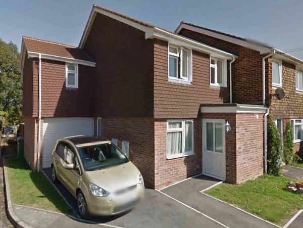 Residential house with a parked car in the driveway on a sunny day.