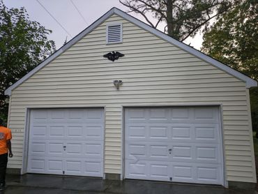 A two-door garage with white doors and yellow siding.