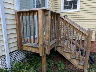 A small wooden staircase leading to a door on a yellow house.