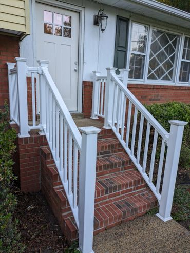 Brick steps with white railings leading to a white door on a house.