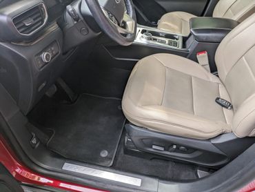 Interior view of a Ford Explorer with beige leather seats and black floor mats.