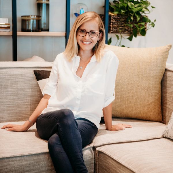 Woman sitting on a beige couch smiling.