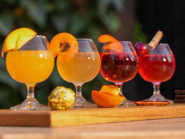 Colorful cocktails garnished with fruit on a wooden board.