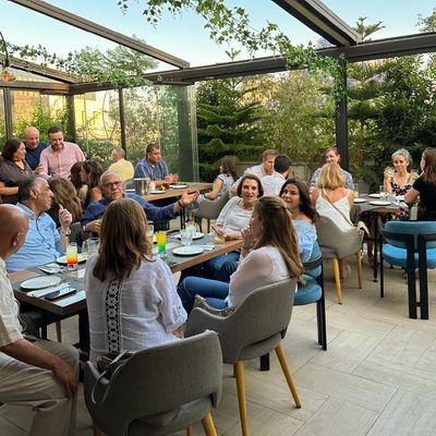 A lively group enjoying a meal together in a bright, glass-enclosed dining area.