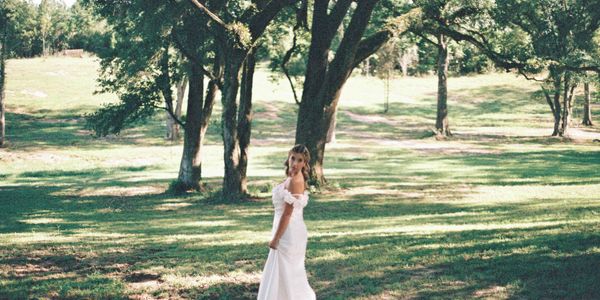 Bride in elegant white gown standing in Oak Alley at Oak Hill Farm outdoor wedding venue