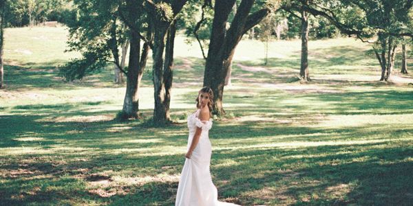 Bride in elegant white gown standing in Oak Alley at Oak Hill Farm outdoor wedding venue