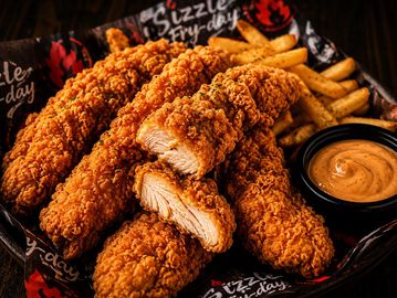 Basket of crispy chicken tenders, fries, and dipping sauce.