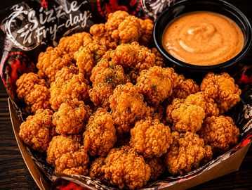 Crispy fried popcorn chicken with dipping sauce.