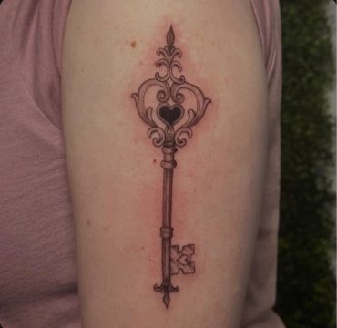 Ornate vintage key tattoo on arm.