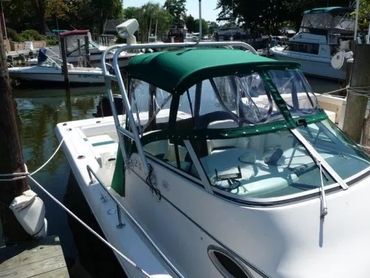 White boat docked with green canopy and clear plastic side panels.