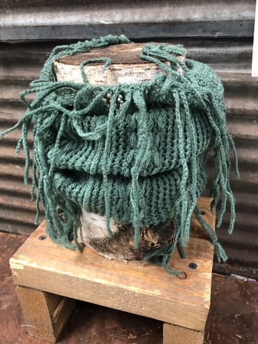 Green knit scarf with fringe on wooden blocks at The Peak in Albertville, MN