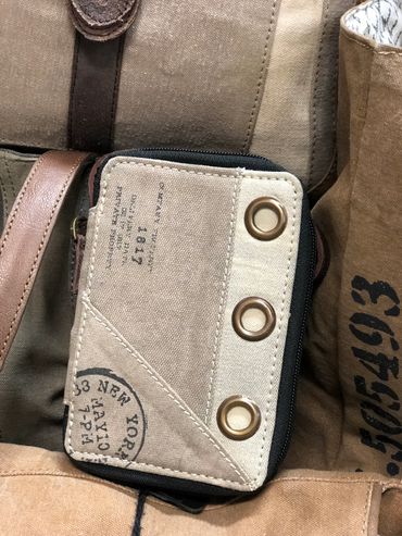 Canvas wallets and bags with metal eyelets and printed text at The Peak in Albertville, MN