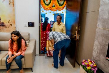 Family gathering at a decorated entrance with a woman sitting on a couch.