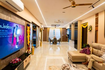 Modern living room with TV, dining area, and a child on a couch.