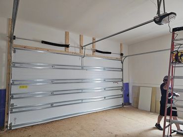 Man working on a garage door installation in a spacious garage.