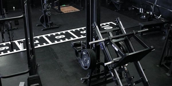Empty gym with weightlifting equipment and mirrors.