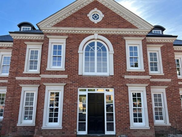 Elegant red brick building with white-trimmed windows and black door.