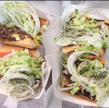 Four sandwiches filled with meat, onions, lettuce, and seasoning on white bread.