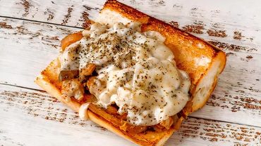 Grilled sandwich with melted cheese and herbs on rustic bread.