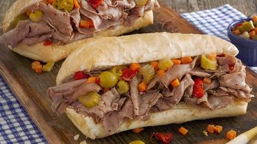 Italian beef sandwich with giardiniera on a wooden board.