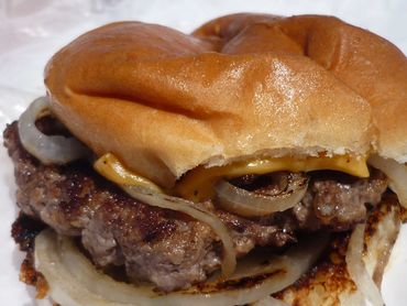 Grilled cheeseburger with onions on a toasted bun.