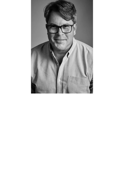 Black and white portrait of a middle-aged man with glasses and a slight smile.