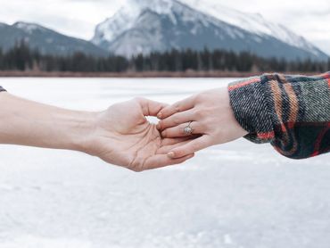 Engaged couple reach for each others hands in Banff National Park.