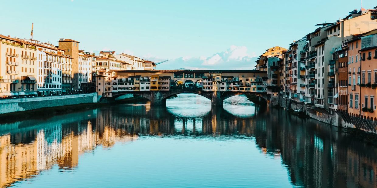 Historic bridge over calm river with buildings on both sides.
