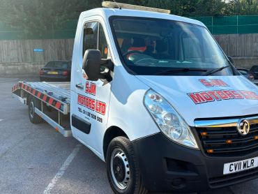 White flatbed tow truck with company logo on the side.