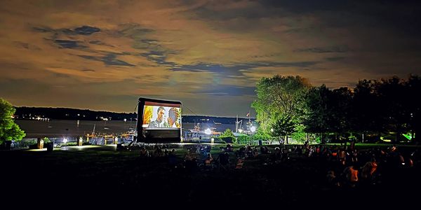 “Black Panther” on a outdoor movie screen, with a river behind it, for movies in the park