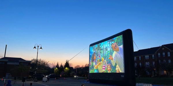 “Encanto” drive in movie on an Extreme 55’ outdoor movie screen with people also sitting outside