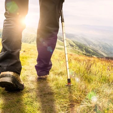 Person hiking with a walking stick in the sunlight.