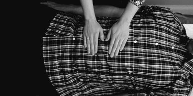 Person with hands on the chest of another in plaid shirt.