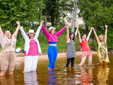 Group of happy women holding hands in water.