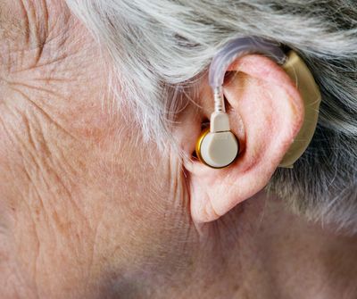 Close up of hearing aid in older person's ear