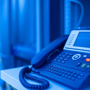 Close-up of a blue office phone with a coiled cord.