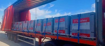 Large Marley-branded boxes secured with blue straps on a truck trailer under a clear sky.
