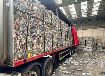 A truck loaded with compressed plastic waste inside a recycling warehouse.