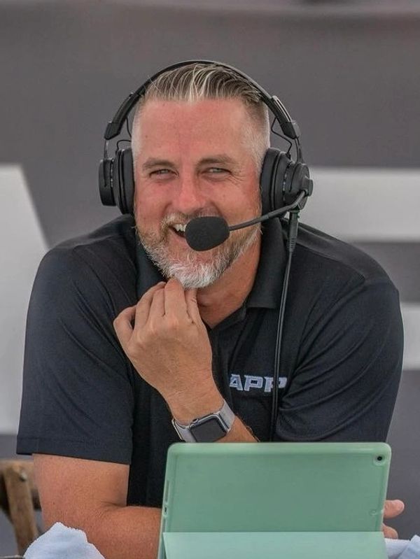 Man wearing headset and speaking into microphone, smiling.