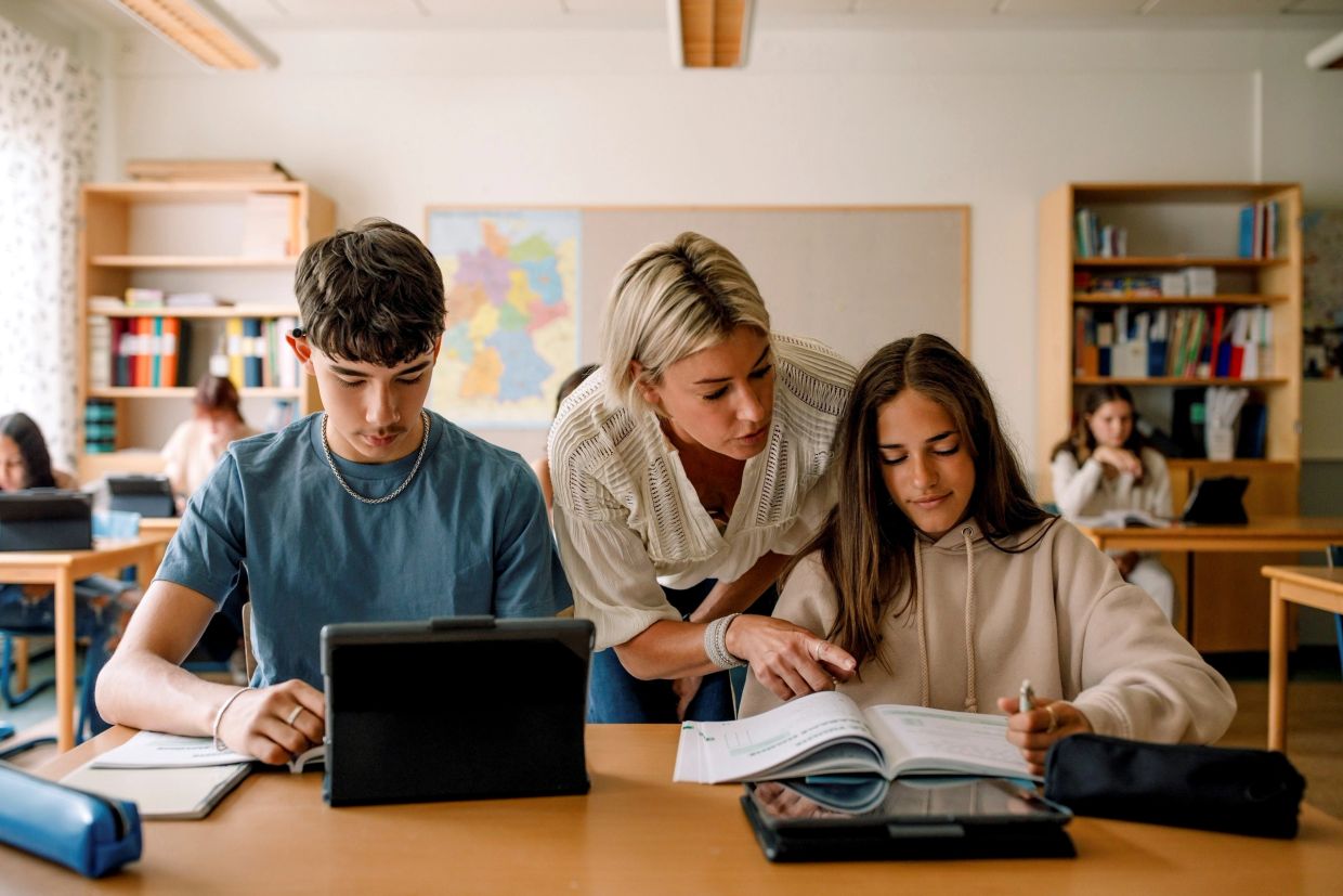 Teacher helping students in a classroom.