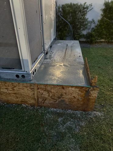 Concrete slab foundation being poured next to an outdoor HVAC unit.