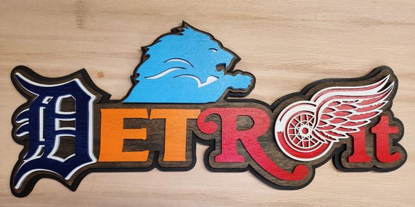 Wooden sign spelling Detroit with sports logos and colors.