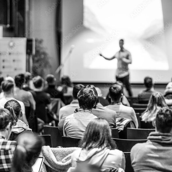 Audience attentively listening to a speaker during a presentation in a conference room.