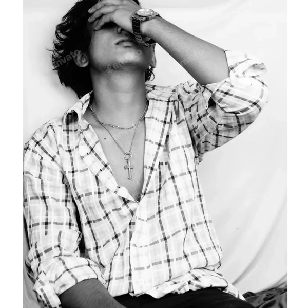 Black and white photo of a man in a checkered shirt covering his face with his hand.