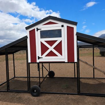 Red and white chicken coop with wire enclosure and wheels.