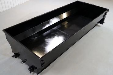 A large, empty black metal container with a shiny surface.