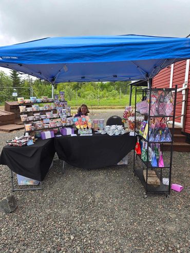 Woman selling various colorful treats and gift bags under a blue canopy.